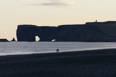 Silhouette people on calm beach