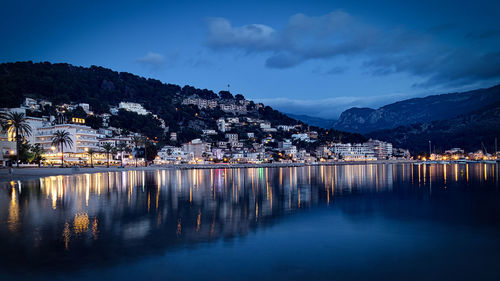 Reflection of illuminated buildings in lake against sky at dusk