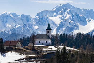 Snow covered buildings and mountains against sky