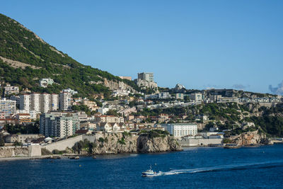 View of city by sea against clear blue sky