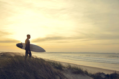 Man on beach against sky during sunset