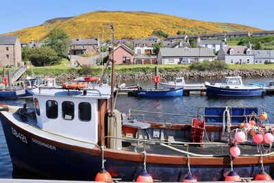 Boats moored in sea by buildings against sky