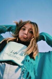 Portrait of young woman against blue sky