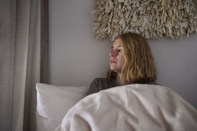 Crying young woman sitting in bed