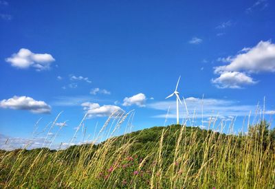 Wind turbine on field against blue sky