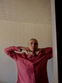 Portrait of young woman standing against wall