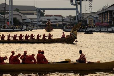 People sitting on boat in river against buildings