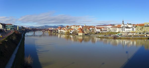 Reflection of buildings in river against blue sky