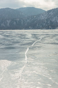 View of beautiful drawings on ice from cracks on the surface of lake teletskoye in winter, russia