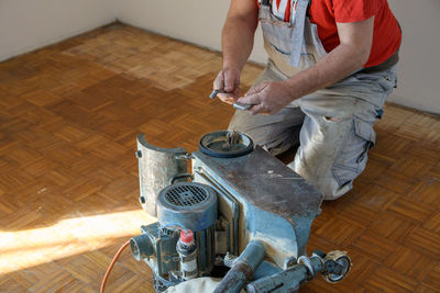 Man sanding hardwood floor with grinding machine