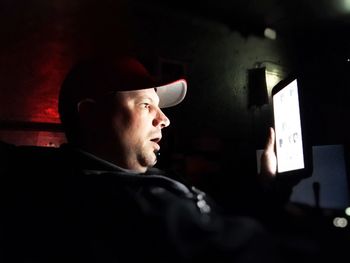 Man using digital tablet while sitting in darkroom