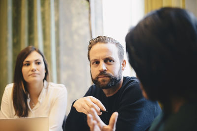 Confident businessman looking at female colleagues during board room meeting