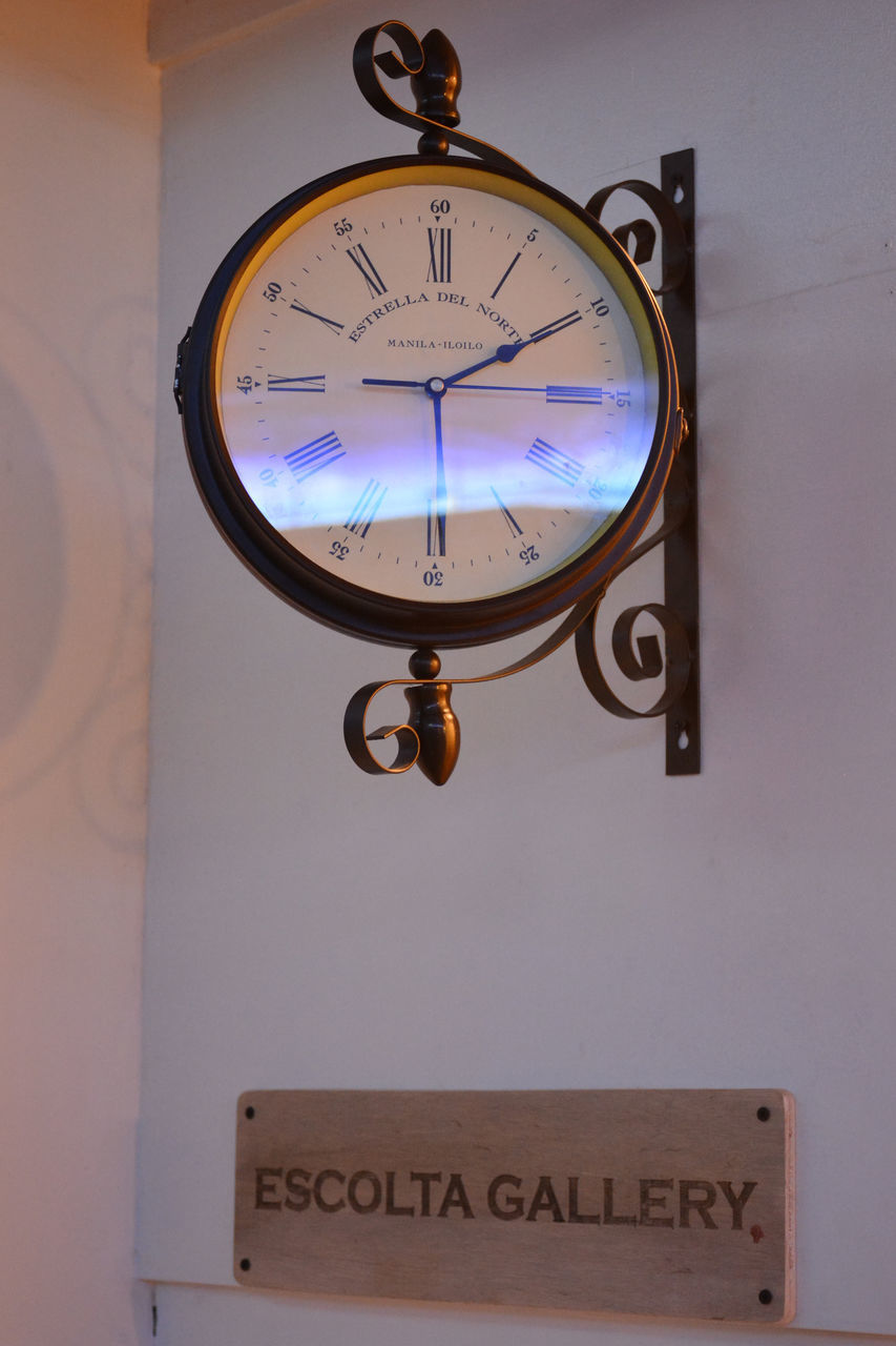 LOW ANGLE VIEW OF CLOCK HANGING AGAINST WALL