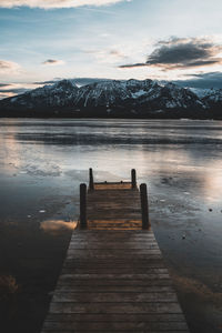 Pier over lake against sky during sunset