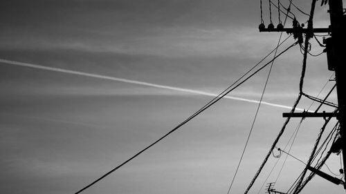 Low angle view of electricity pylon against cloudy sky