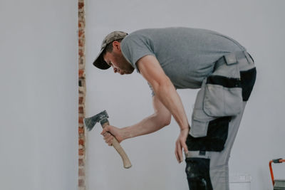 A young caucasian male builder clears a doorway using a crowbar.