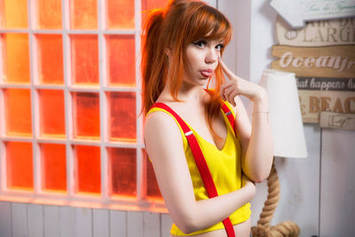 Beautiful young woman standing against brick wall