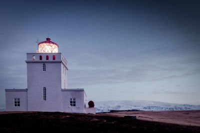 Lighthouse by sea against sky cold mountain basaltic covered in snow 