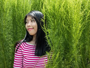 Portrait of smiling young woman standing against plants