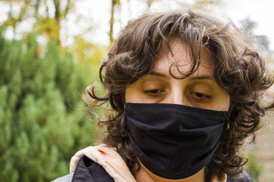 Woman's portrait with black medical face mask, nature background