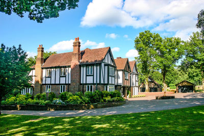 Houses by trees and buildings against blue sky