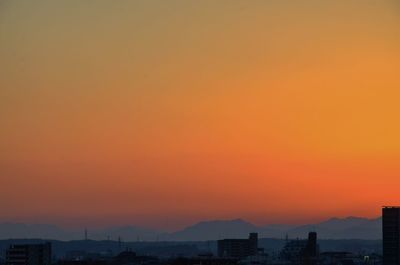 Silhouette cityscape against orange sky