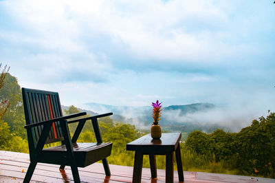 Empty chairs and table against sky