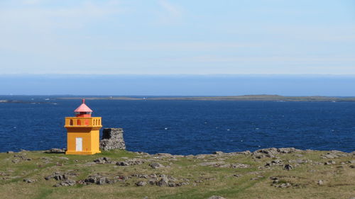 Lighthouse by sea against sky