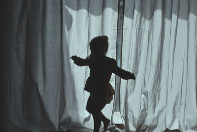 Side view of silhouette woman standing at home