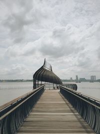 Pier on sea against cloudy sky