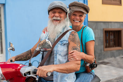 Side view of a modern senior couple riding on a motorcycle while driving through town