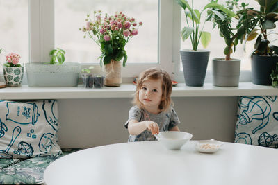 A little girl is sitting at the kitchen table eating soup. high quality photo