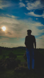 Rear view of silhouette man standing on field against sky during sunset