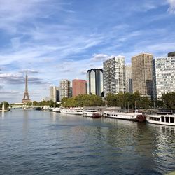 River by modern buildings against sky in city