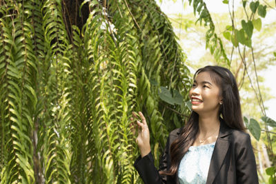 Young woman standing against plants