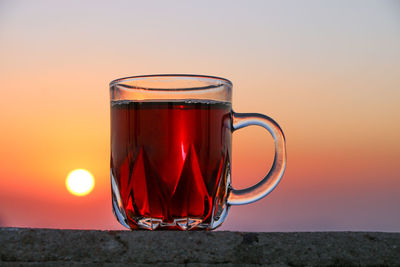 Close-up of tea in cup against orange sky