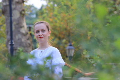 Portrait of smiling woman standing against plants