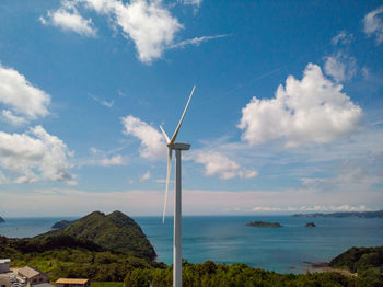 Wind turbines by sea against sky