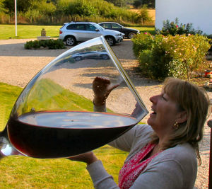 Optical illusion of woman drinking red wine from large glass