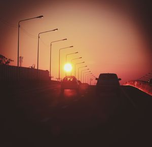 Silhouette street against sky at sunset