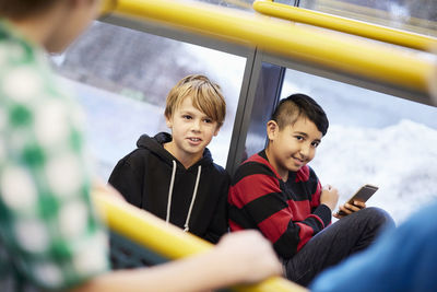 Boys looking away while leaning on glass in middle school