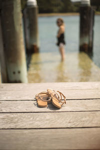 Close-up of sandals on boardwalk against woman