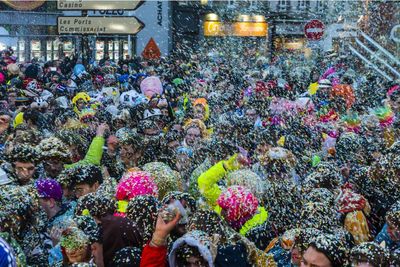 Crowd throwing colorful confetti in city during celebration