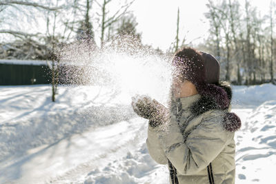 Boy standing in snow against clear sky during winter