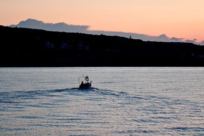 Silhouette boat sailing on sea against sky at sunset