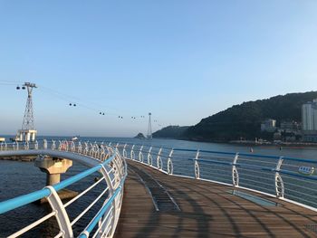 Pier over sea against clear blue sky