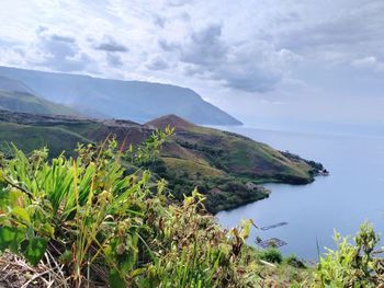 Scenic view of sea and mountains against sky