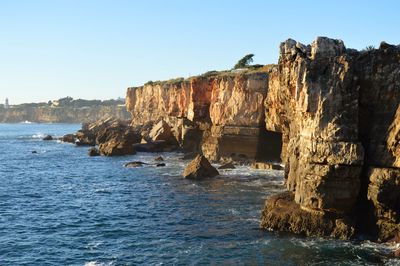 Rock formation on beach against clear sky