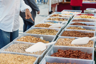 Midsection of customer pointing at dry fruits at market