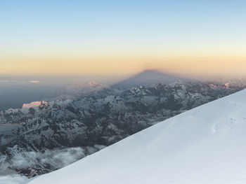 Scenic view of snow covered mountains against sky during sunset